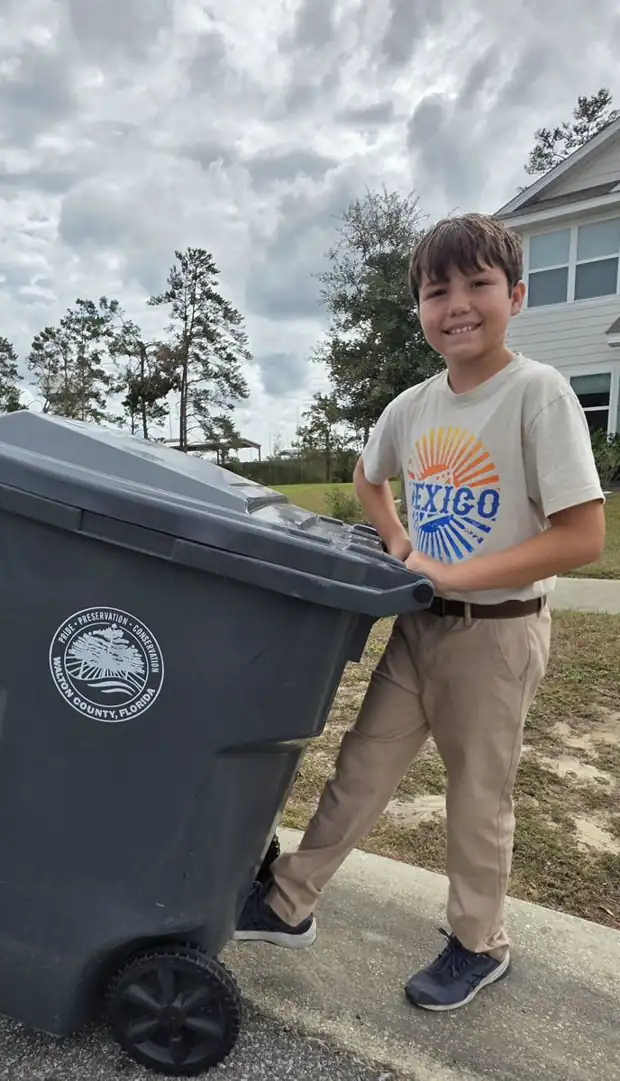 Levi rolling a trash can to the curb
